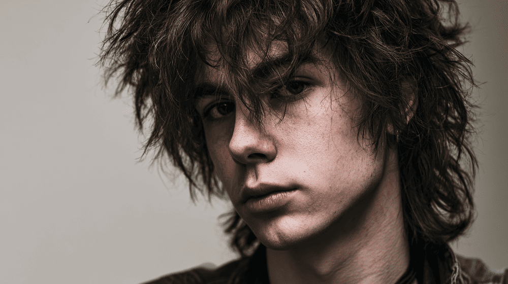 jongeman met een ongestyled wulf cut mullet kapsel