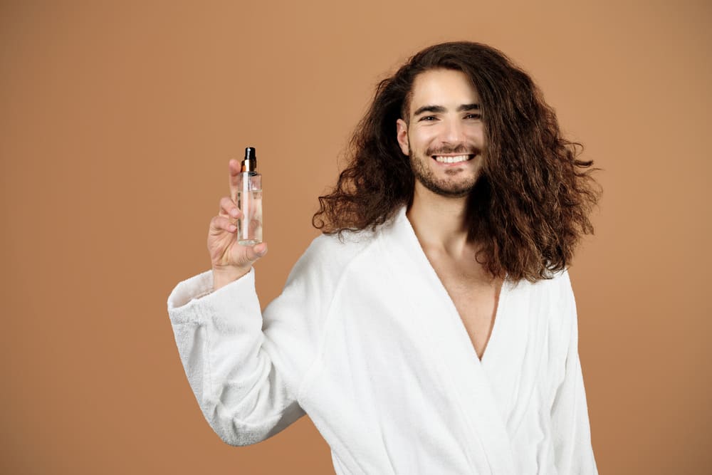 man met lang haar laat serum zien om haar te verzorgen