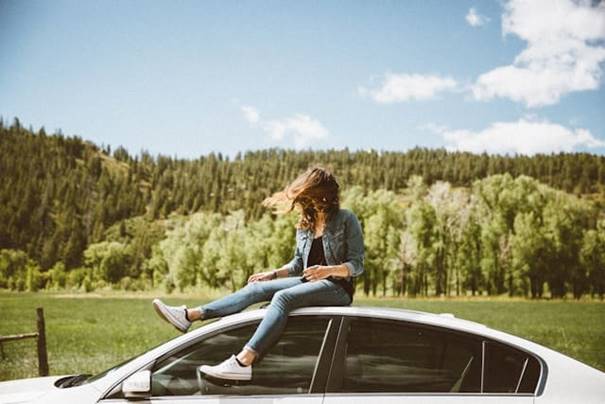 Vrouw zit op het dak van de auto