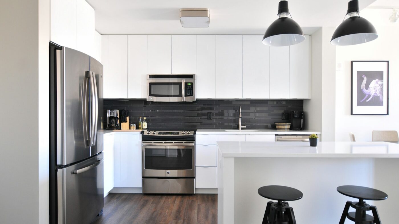 Moderne keuken met witte kasten, zwart tegelwerk en roestvrijstalen apparatuur