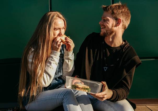 Twee mensen lachen en lunchen na hoofdmaaltijd overslaan