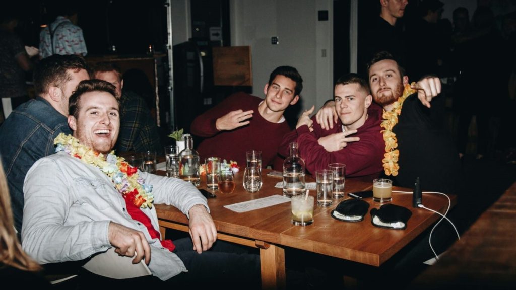 Jongens vieren een feestelijke avond met drankjes en hawaiikransen tijdens een bachelor trip