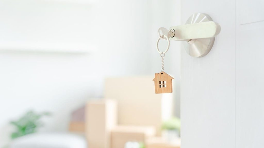 Sleutel met huisvormige hanger in deur als symbool voor verhuizen en professionele ontwikkeling