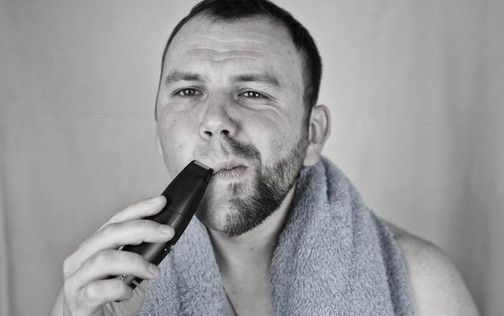man scheert zijn baard met de beste scheerapparaten