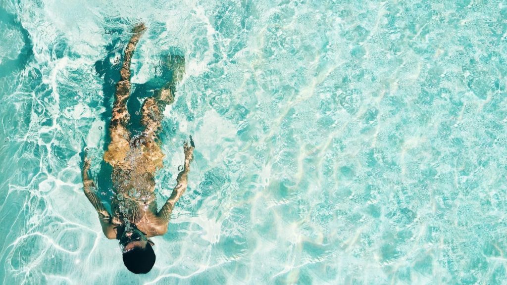 Persoon zwemt in helder water met zonnebrand SPF 50 bescherming tijdens zonnige dag